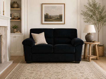 Black corduroy loveseat sofa with plush cushions in a warm and elegant living room.