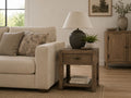 Rustic wood end table with a drawer and open lower shelf, styled beside a cream sofa in a cozy transitional living room.