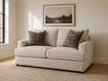 Cream fabric loveseat with patterned accent pillows in a bright modern living room.