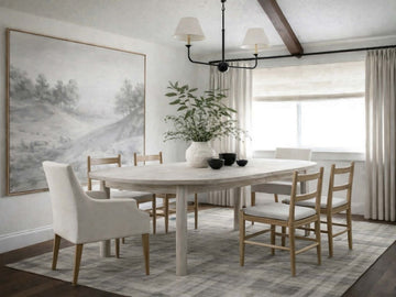 Light wood oval dining table with pedestal legs and mixed dining chairs in a bright, neutral dining room.
