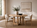 Round light wood dining table with a geometric pedestal base and four upholstered dining chairs in a modern dining room.