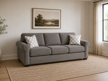 Gray fabric sofa sleeper with patterned accent pillows in a cozy modern living room.