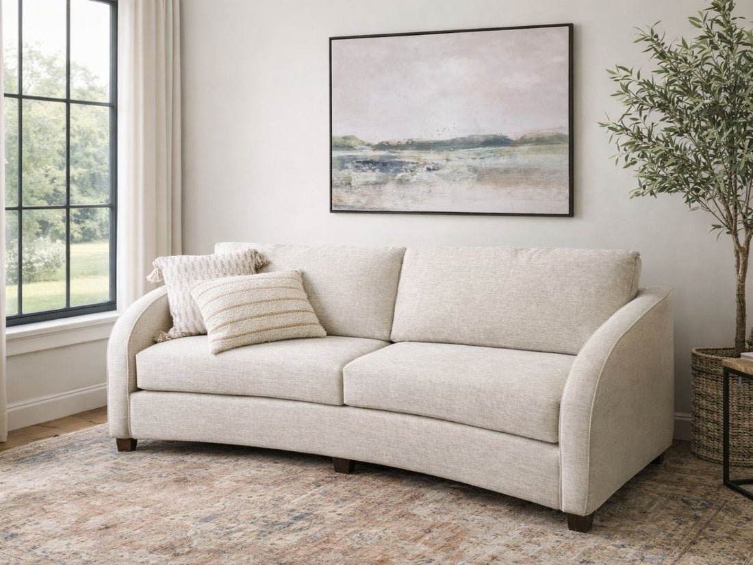 A light upholstered sofa with a curved silhouette in a calm, neutral living space.