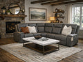 A gray leather sectional sofa styled in a warm, rustic living room with a stone fireplace.