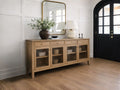 Light wood sideboard with glass-front cabinet doors and storage drawers, styled in a bright entryway with modern décor and a large wall mirror.