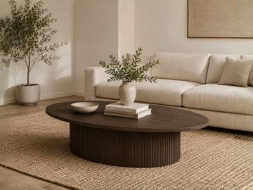 Oval wood coffee table with a fluted base in a modern living room.