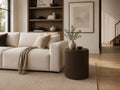 Round fluted side table beside a cream sofa in a modern living room.