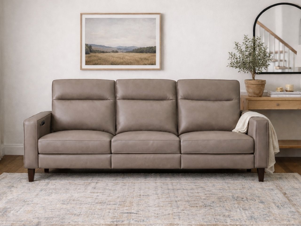 A taupe leather sofa styled in a warm, modern living space.