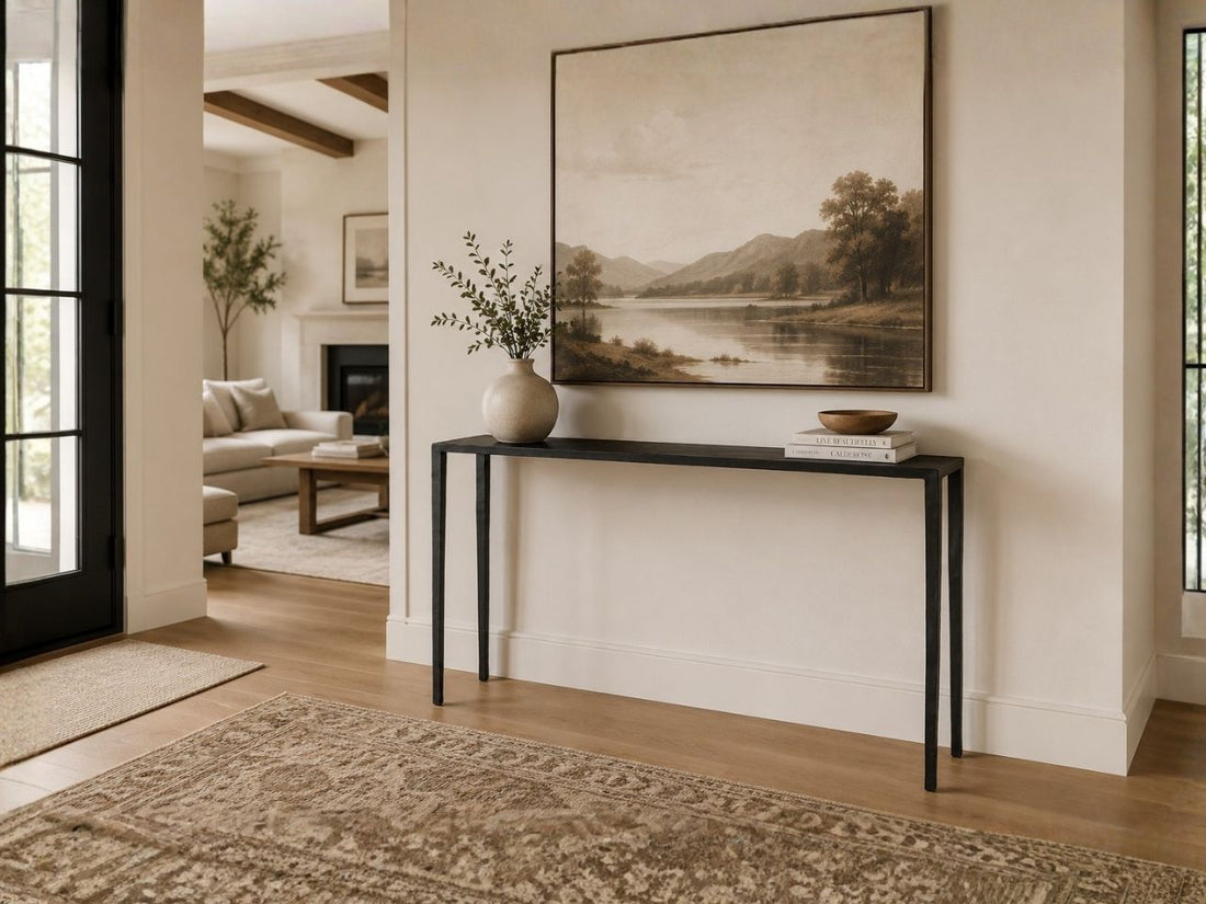 Minimalist black console table styled beneath a large landscape artwork in a warm, modern hallway.