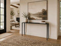Minimalist black console table styled beneath a large landscape artwork in a warm, modern hallway.