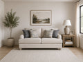 Cream-colored loveseat with patterned blue and gray pillows in a bright, cozy living room.