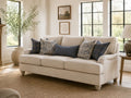 Light fabric sofa with patterned blue accent pillows in a bright, cozy living room.