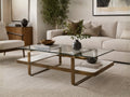 Glass-top coffee table with a metal frame and lower shelf, styled in a modern living room.