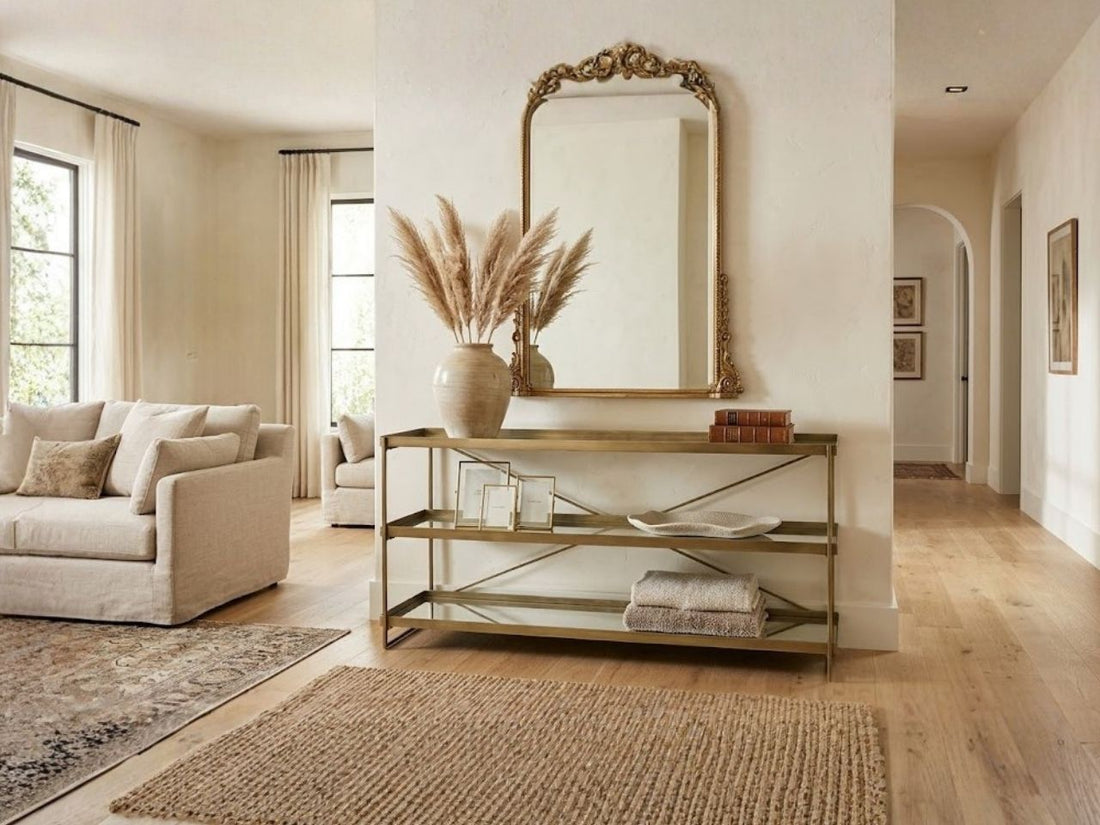 Gold metal console table with open shelves styled in a bright entryway.