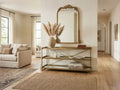 Gold metal console table with open shelves styled in a bright entryway.