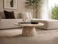 Round wood coffee table with a pedestal base styled in a cozy living room with a sectional sofa.