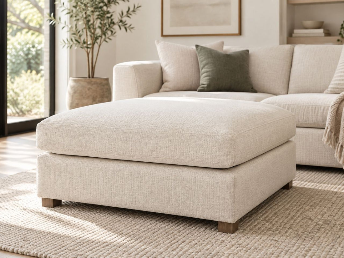 Cream upholstered ottoman in a luxurious modern living room, featuring soft neutral tones and elegant contemporary furniture in Calgary.