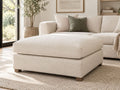 Cream upholstered ottoman in a luxurious modern living room, featuring soft neutral tones and elegant contemporary furniture in Calgary.