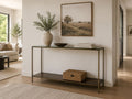 Glass-top console table with a metal frame styled in a bright modern entryway with neutral décor.
