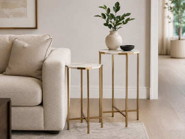 Marble top nesting side tables with gold metal frames beside a cream sofa.