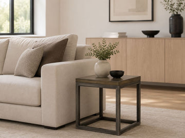 Modern square solid wood side table with an open cube base, styled beside a cream sofa in a minimalist contemporary living room.